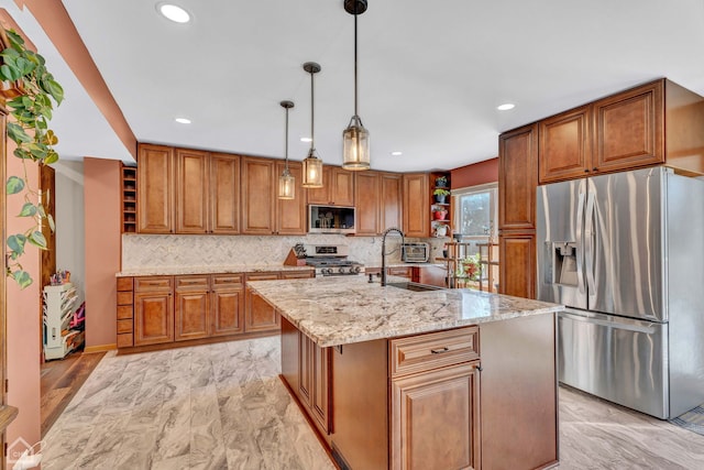 kitchen with stainless steel appliances, sink, decorative light fixtures, light stone counters, and an island with sink