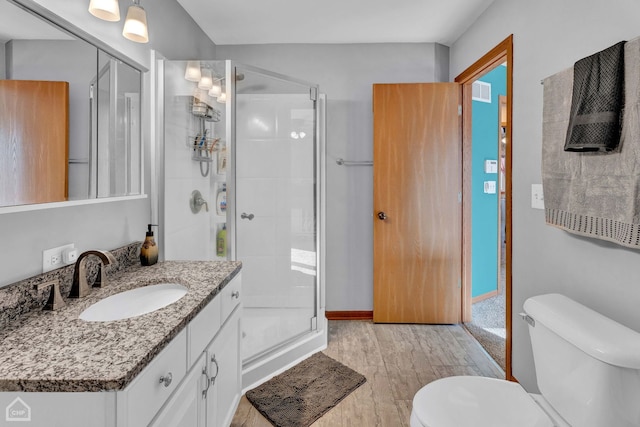 bathroom featuring toilet, a shower with door, vanity, and hardwood / wood-style floors