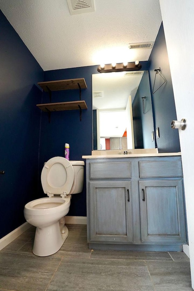 bathroom featuring toilet, a textured ceiling, and vanity