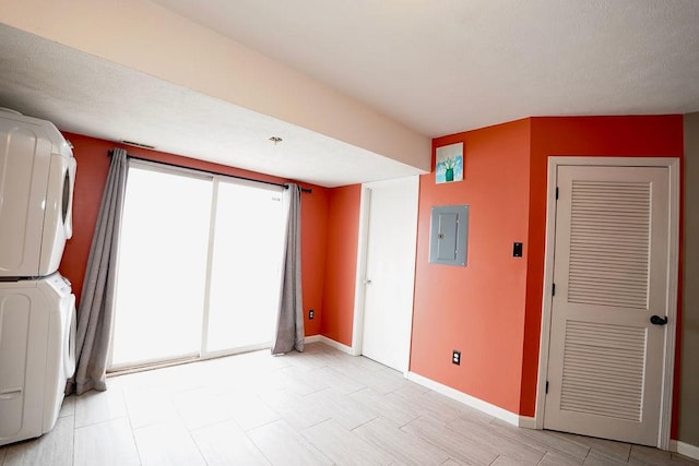 interior space with electric panel and stacked washer / dryer