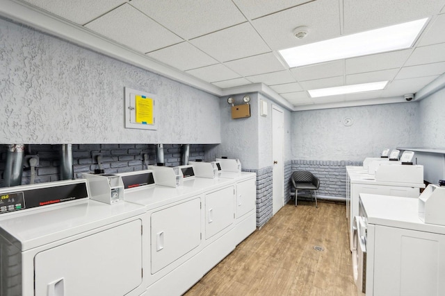 laundry room with separate washer and dryer, brick wall, and light hardwood / wood-style floors