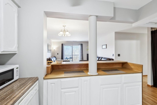 kitchen featuring a notable chandelier, white appliances, decorative columns, white cabinets, and decorative light fixtures