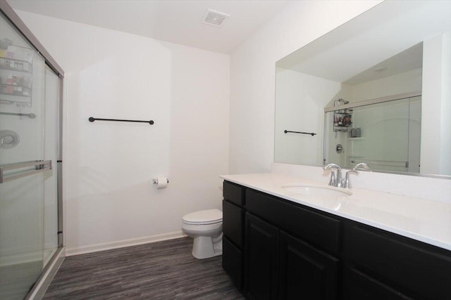 bathroom featuring walk in shower, hardwood / wood-style floors, vanity, and toilet