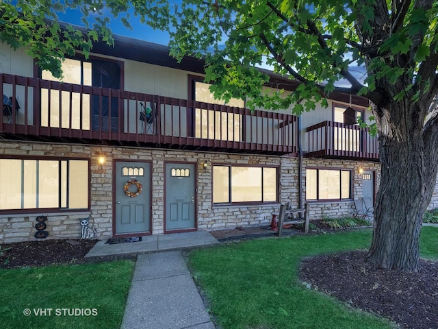 view of front of house with a balcony and a front lawn