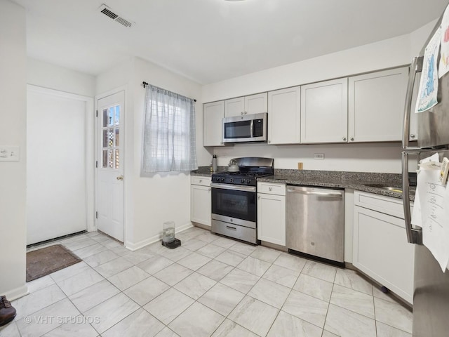 kitchen featuring white cabinets, dark stone counters, and appliances with stainless steel finishes