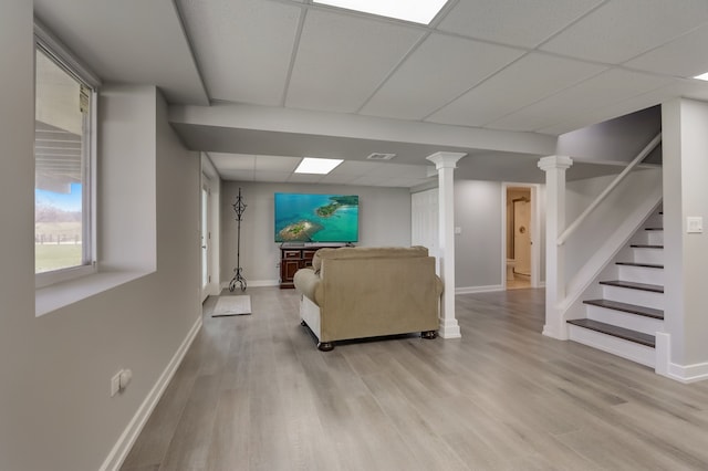 living room featuring a paneled ceiling, decorative columns, and light hardwood / wood-style flooring