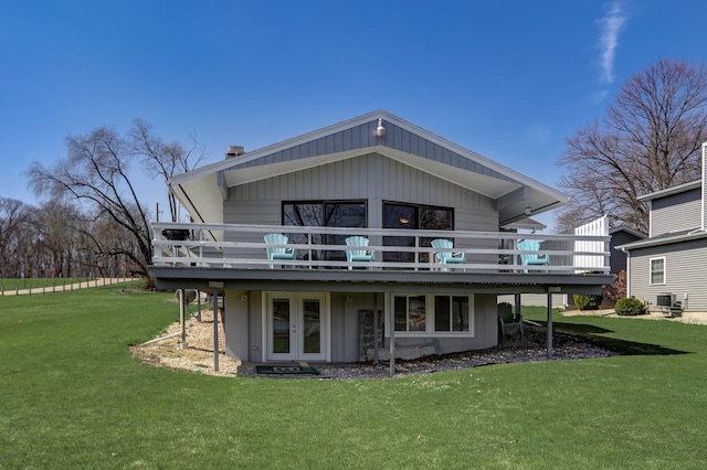 rear view of house with cooling unit, a wooden deck, a yard, and french doors