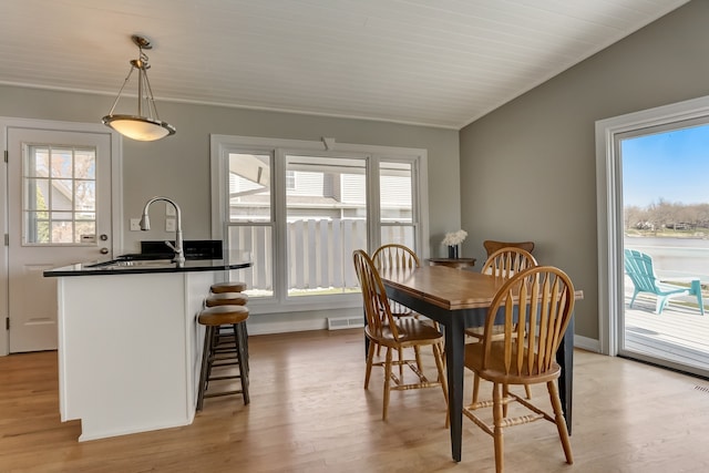 dining space with lofted ceiling, a healthy amount of sunlight, and light wood-type flooring