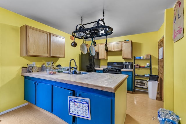 kitchen with black appliances, tile counters, sink, kitchen peninsula, and light wood-type flooring