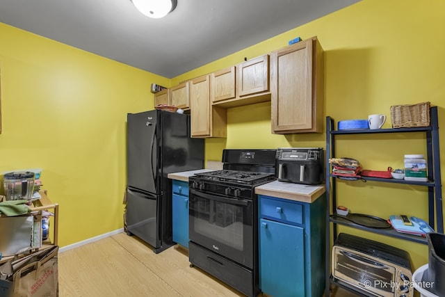 kitchen featuring black appliances, tile countertops, light brown cabinetry, and light hardwood / wood-style floors