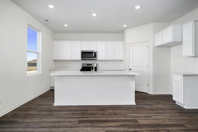 kitchen featuring sink, white cabinets, an island with sink, dark hardwood / wood-style flooring, and appliances with stainless steel finishes