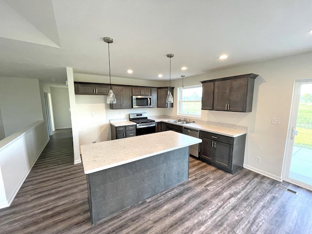 kitchen featuring sink, a center island, hanging light fixtures, appliances with stainless steel finishes, and dark hardwood / wood-style floors