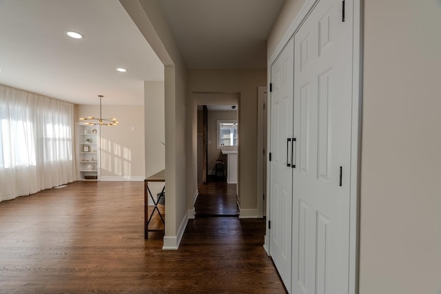 corridor with dark hardwood / wood-style flooring and a chandelier