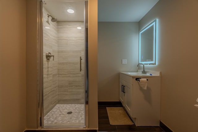 bathroom featuring a shower with door and vanity