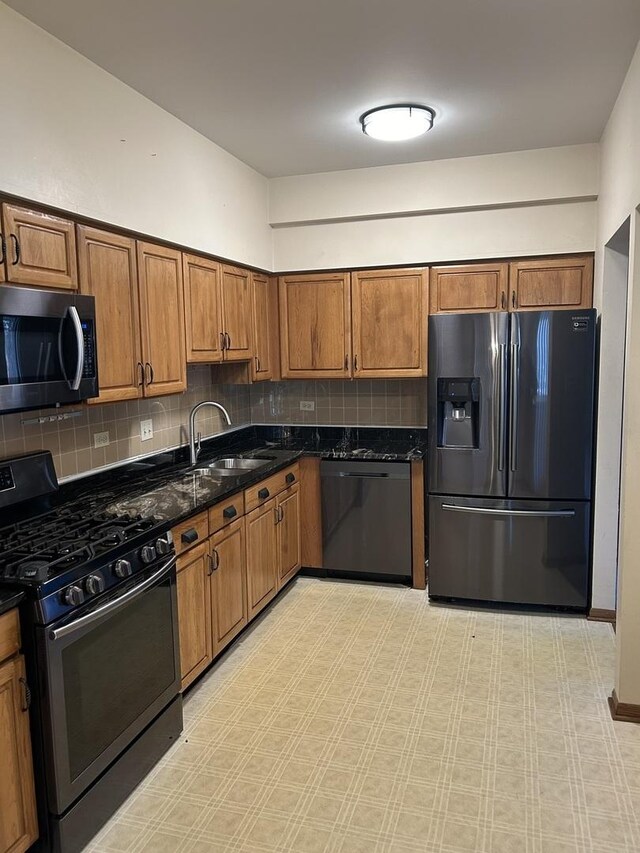 kitchen with sink, dark stone countertops, black appliances, and decorative backsplash