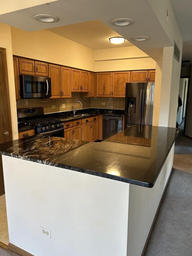 kitchen featuring appliances with stainless steel finishes, dark stone countertops, backsplash, and sink