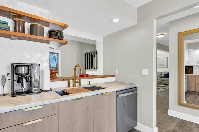 kitchen featuring light stone countertops, dishwasher, dark hardwood / wood-style flooring, tasteful backsplash, and sink