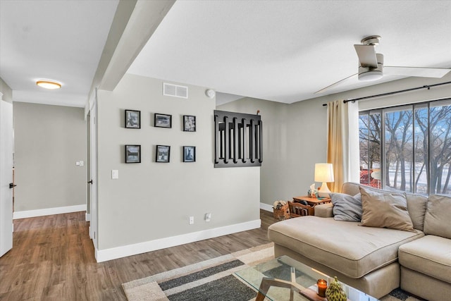 living room with ceiling fan, wood-type flooring, and beamed ceiling