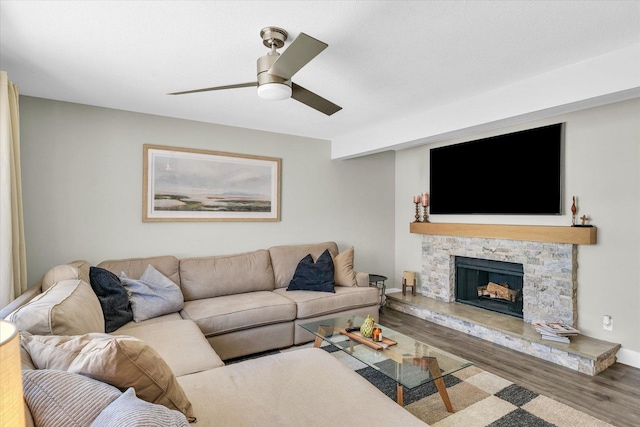 living room featuring ceiling fan, a fireplace, and wood-type flooring