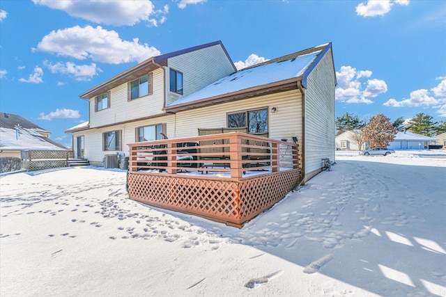 snow covered rear of property with a deck and cooling unit