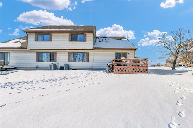 snow covered house with a wooden deck and cooling unit