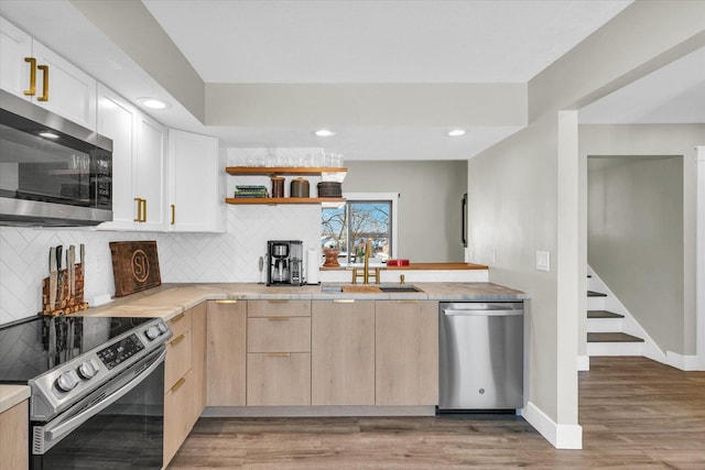 kitchen with backsplash, sink, light hardwood / wood-style flooring, appliances with stainless steel finishes, and light brown cabinets