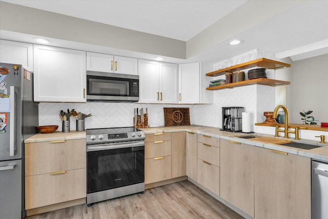 kitchen with backsplash, sink, stainless steel appliances, and light hardwood / wood-style flooring