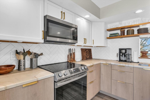 kitchen featuring light brown cabinetry, light stone countertops, backsplash, and appliances with stainless steel finishes