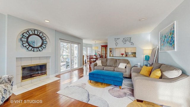 living room featuring a tile fireplace and light hardwood / wood-style flooring