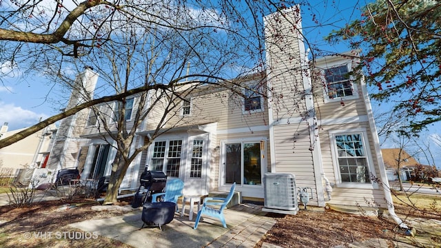 rear view of house with central AC unit and a patio