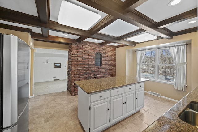 kitchen with a kitchen island, white cabinetry, stainless steel fridge, dark stone counters, and light carpet