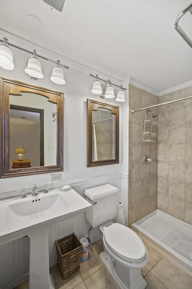 bathroom featuring crown molding, tiled shower, tile patterned floors, and toilet