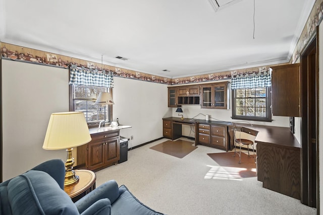 office space featuring light carpet, built in desk, ornamental molding, and plenty of natural light