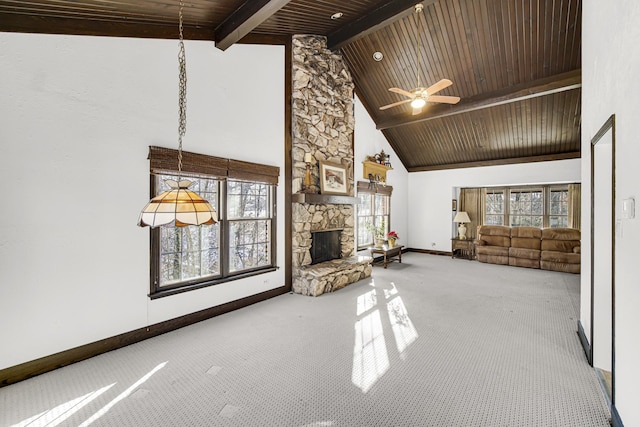 unfurnished living room with a stone fireplace, high vaulted ceiling, ceiling fan, beam ceiling, and carpet