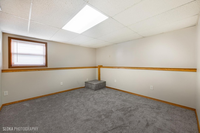 empty room featuring a paneled ceiling and carpet