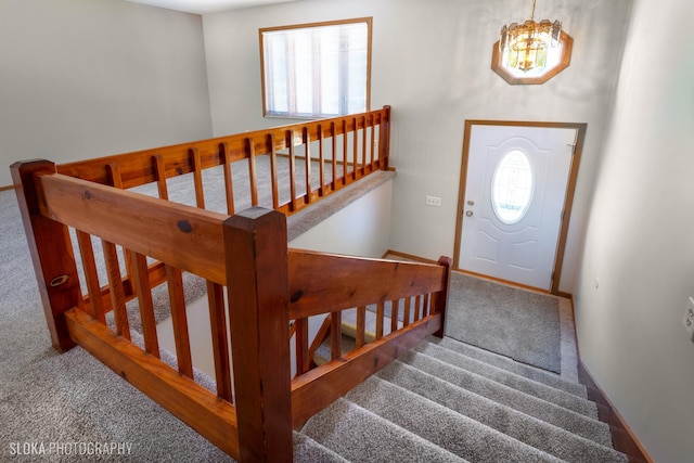 carpeted foyer entrance featuring a notable chandelier