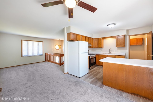 kitchen featuring light colored carpet, ceiling fan, white refrigerator, sink, and gas range