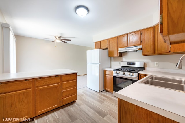 kitchen featuring light hardwood / wood-style floors, white refrigerator, ceiling fan, stainless steel range with gas stovetop, and sink