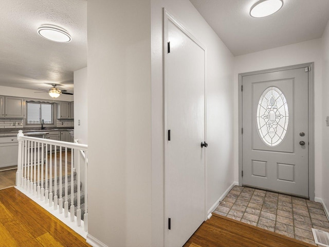 entrance foyer featuring ceiling fan, sink, a textured ceiling, and wood-type flooring