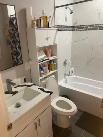 full bathroom featuring toilet, tiled shower / bath combo, tile patterned flooring, and vanity