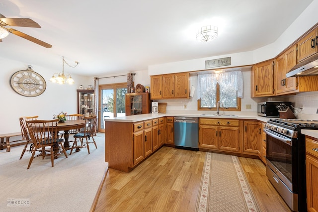 kitchen featuring kitchen peninsula, stainless steel appliances, decorative backsplash, decorative light fixtures, and sink