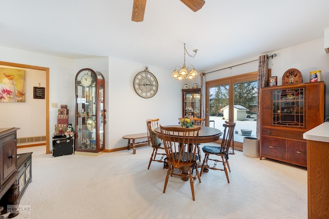 carpeted dining room with ceiling fan with notable chandelier