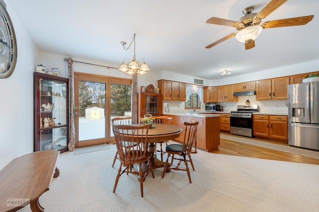 dining room featuring ceiling fan with notable chandelier, light colored carpet, and sink