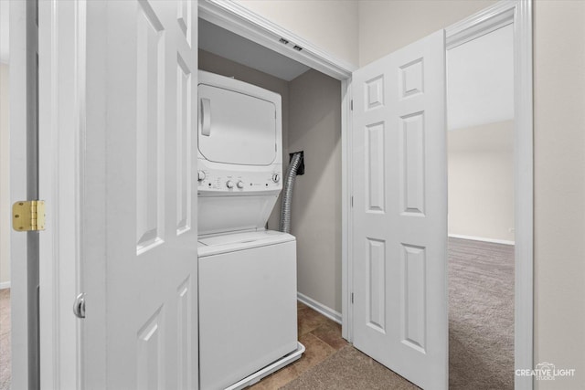 washroom featuring stacked washing maching and dryer and dark carpet