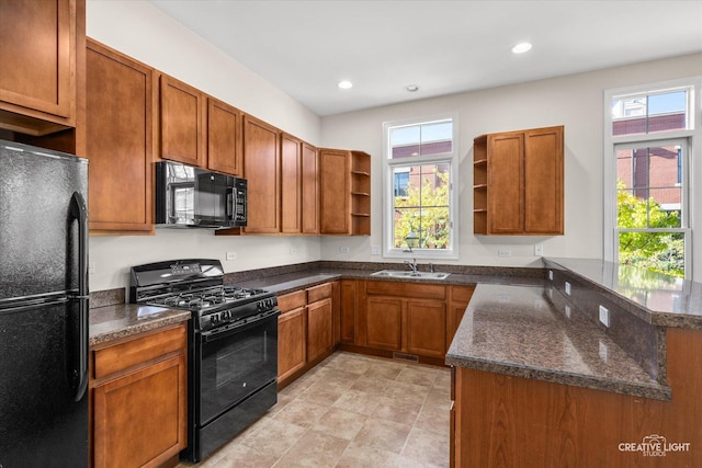 kitchen with black appliances, dark stone counters, sink, and kitchen peninsula