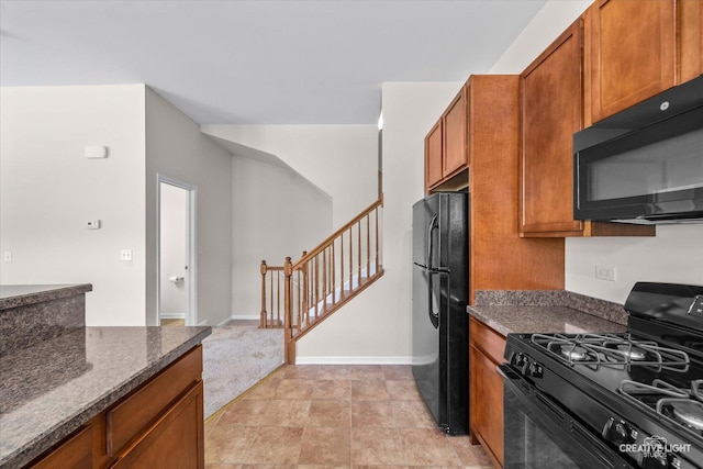 kitchen featuring dark stone counters and black appliances