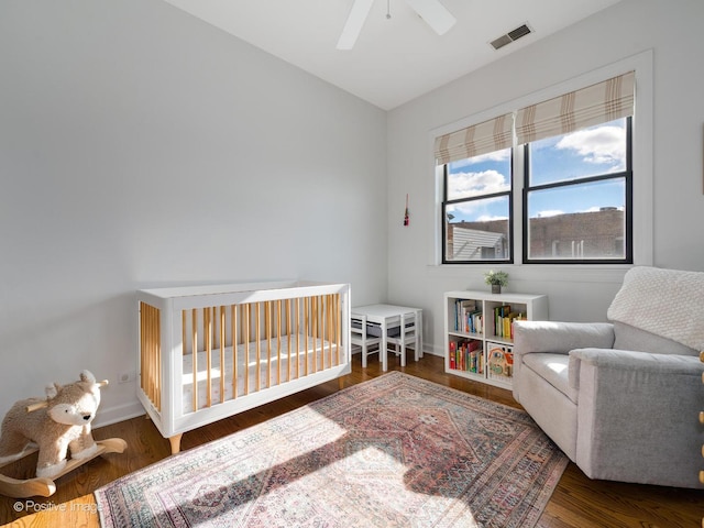 bedroom with dark hardwood / wood-style flooring, ceiling fan, vaulted ceiling, and a nursery area