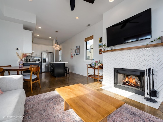 living room with ceiling fan, dark hardwood / wood-style flooring, and a fireplace