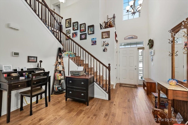 foyer entrance featuring a high ceiling, light hardwood / wood-style floors, and a notable chandelier