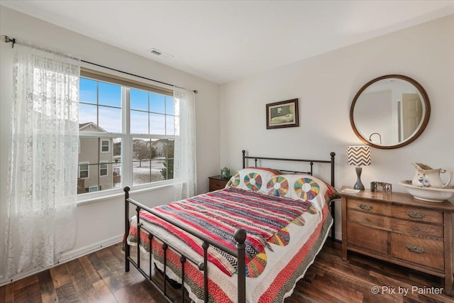 bedroom with dark wood-type flooring and multiple windows